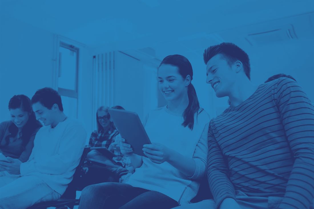A group of young people smiling and working together on a tablet
