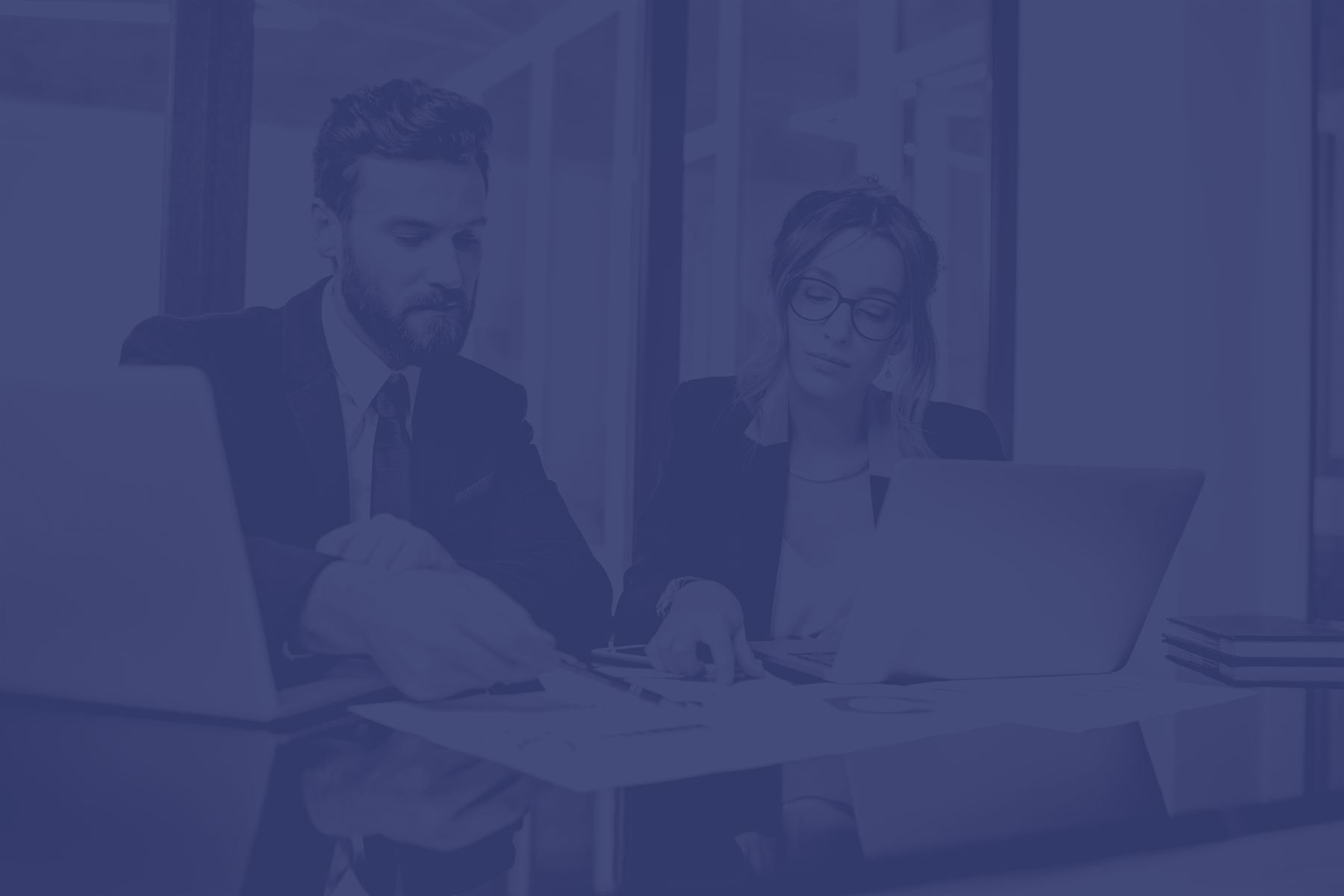 Consulenti IT al lavoro con portatili e documenti in ufficio