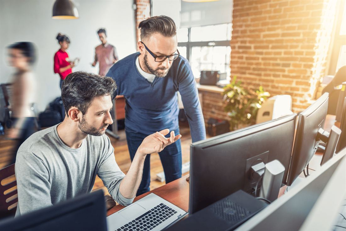 Due sviluppatori discutono il codice davanti a più monitor
