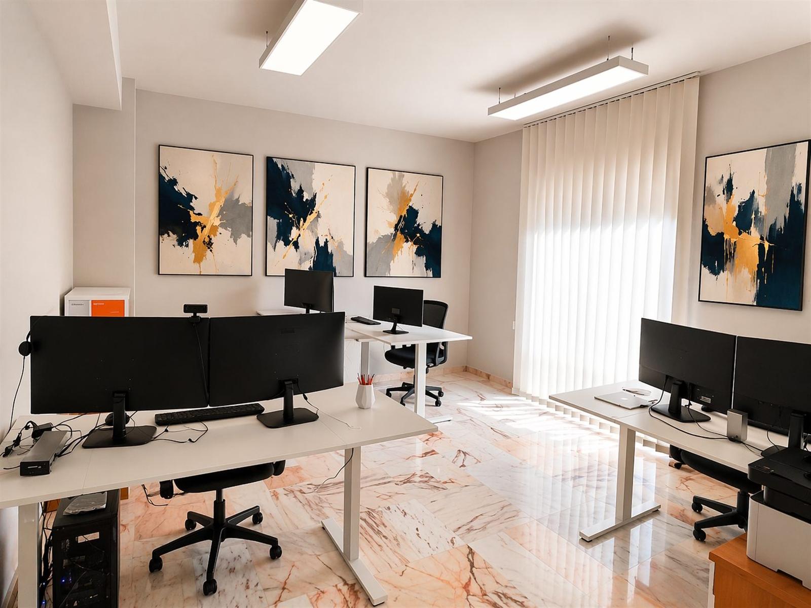 Ufficio operativo della sede Reengineering a Cosenza con monitor e quadri astratti